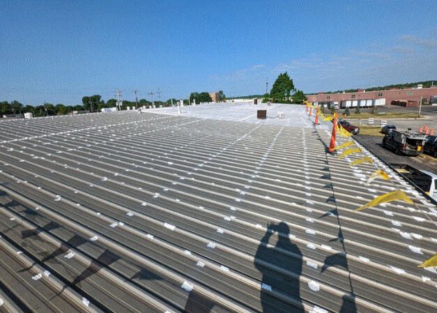 Completed flat roof coating on a commercial building with safety pennants