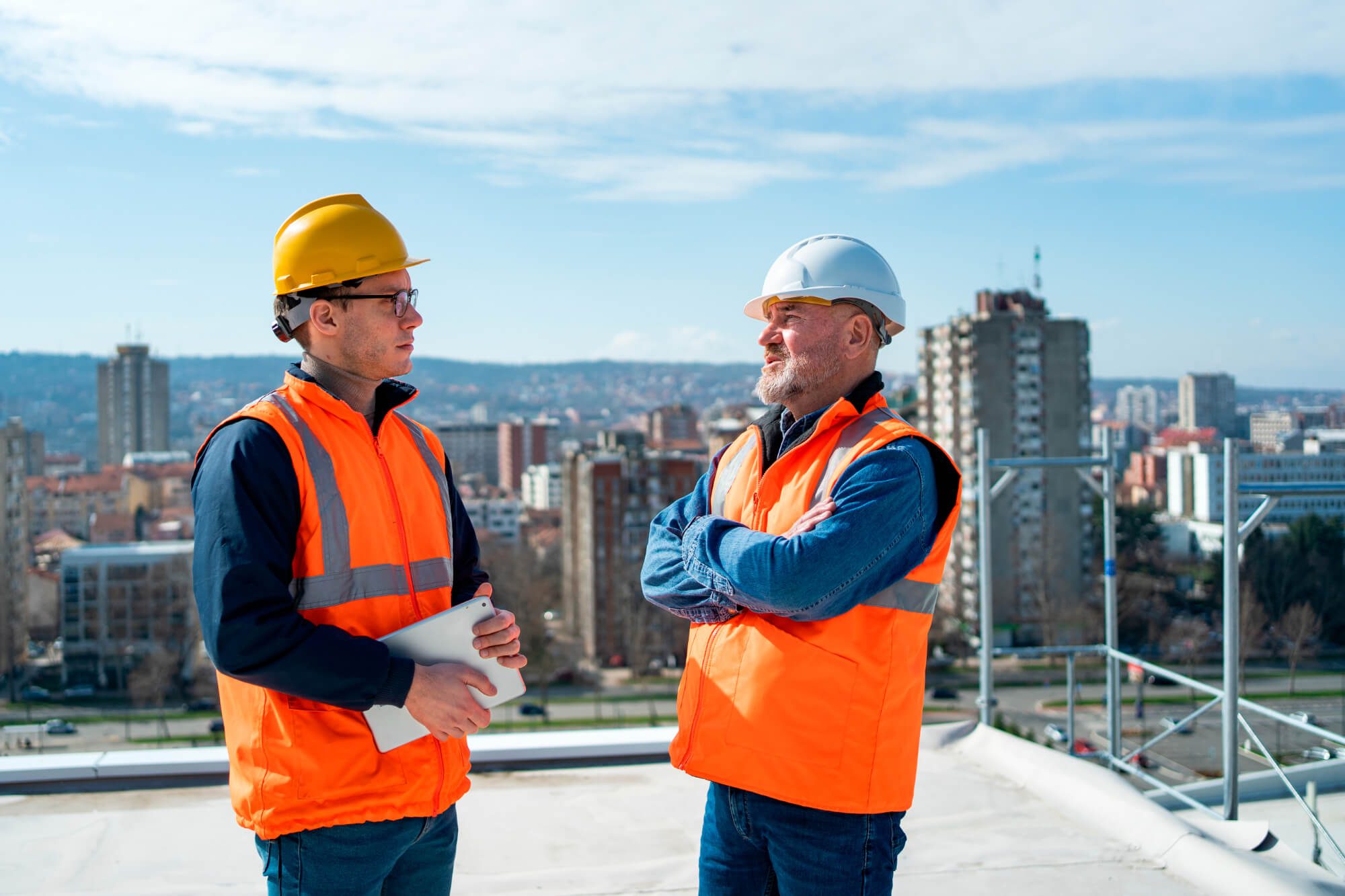 Two roofing professionals discussing a project on a commercial rooftop